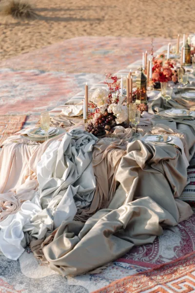 Desert wedding reception table at golden hour with candles and autumnal florals at Al Maha Resort, Dubai, design by Zahra Studio Events
