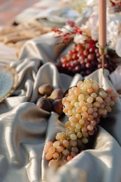 Desert wedding tablescape detail with grapes, fruit and draped silver fabric at Al Maha Resort, styling by Zahra Studio Events
