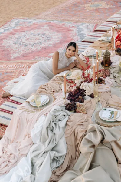 Guest seated at a low desert reception table with rugs and cushions at Al Maha Resort, Dubai, design by Zahra Studio Events