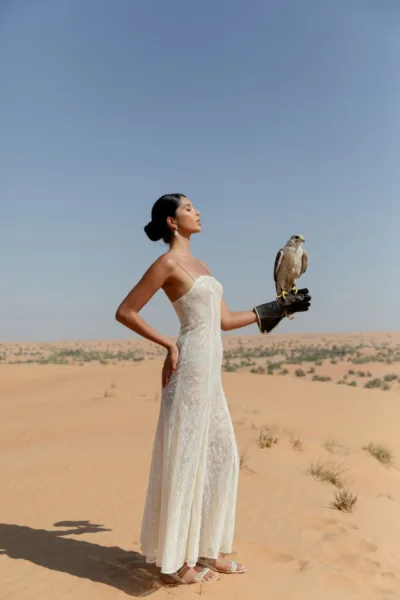 Bride in white holding a falcon in the desert at Al Maha Resort, a Dubai destination wedding editorial