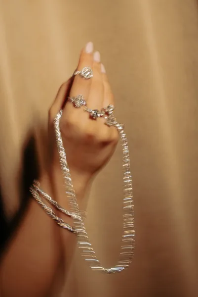 Close-up of a bride's hand wearing rings and crystal bracelets in warm golden light, a wedding jewellery detail