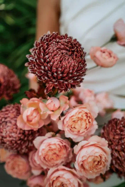 Bride holding a bridal bouquet of peach roses and burgundy chrysanthemums, floral design by Zahra Studio Events