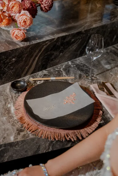 Peach rose tablescape detail with a gold-motif plate on a marble surface, wedding styling by Zahra Studio Events