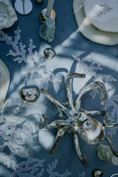 Overhead view of a blue-toned coastal wedding tablescape with florals, tablescape design by Zahra Studio Events