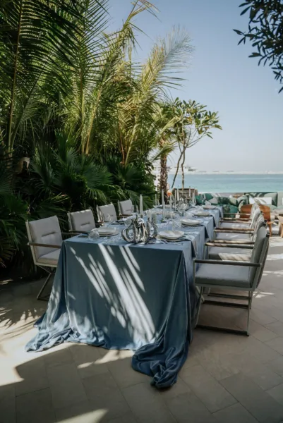 Long wedding reception table with blue linens overlooking the sea, a Mediterranean coastal wedding by Zahra Studio Events