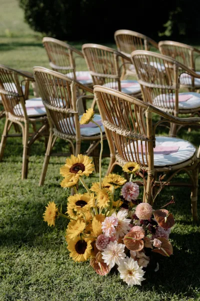 Tuscan wedding ceremony aisle lined with cane chairs and sunflower arrangements, design by Zahra Studio Events