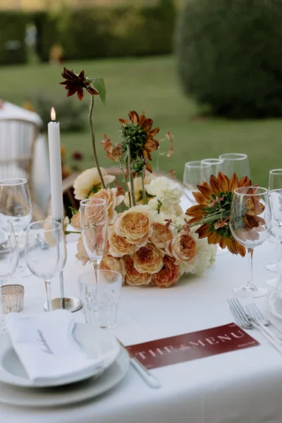 Peach floral centrepiece with a menu card on a Tuscan wedding reception table, tablescape design by Zahra Studio Events