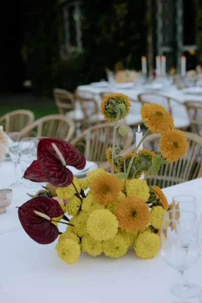 Bold yellow and burgundy floral centrepiece on a Tuscan wedding reception table, floral design by Zahra Studio Events