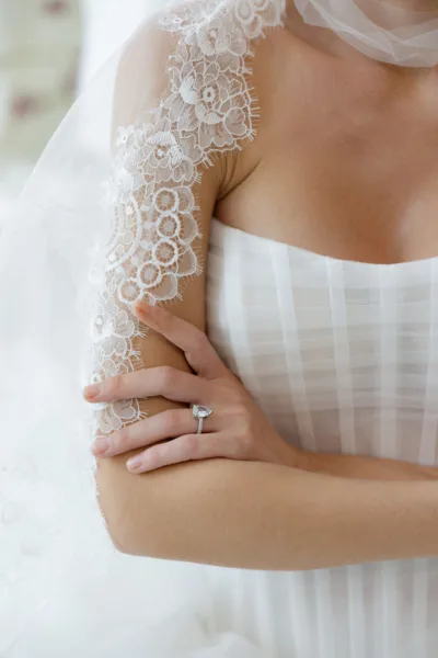 Close-up detail of a bride's white textured gown and lace sleeve at a luxury wedding