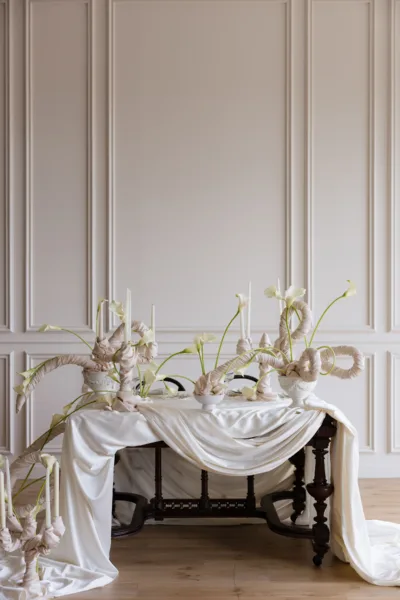 Console table with draped white fabric and a floral arrangement, elegant wedding styling by Zahra Studio Events
