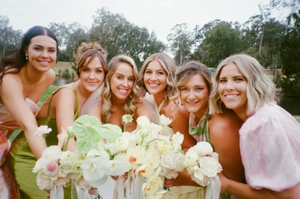 Bride with her bridesmaids holding pastel wedding bouquets, photographed on 35mm film by The Light Photo & Film.