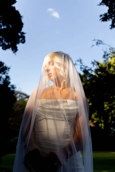 Editorial bridal portrait beneath a sheer veil at golden hour, photographed on 35mm film by The Light Photo & Film.