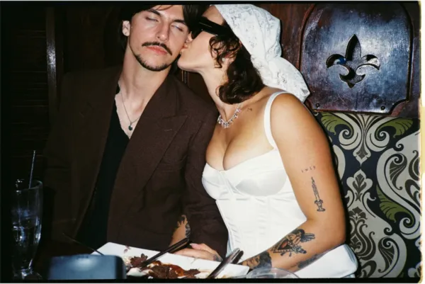 Bride in a modern corset wedding dress and veil kissing the groom at their reception, photographed on 35mm film by The Light Photo & Film.