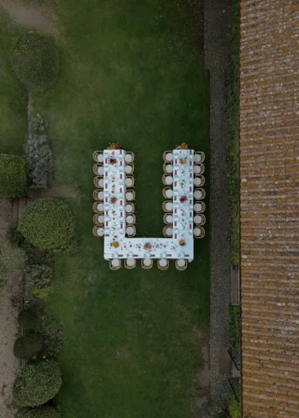 Aerial view of a Tuscan garden wedding ceremony with white chairs arranged on a manicured lawn