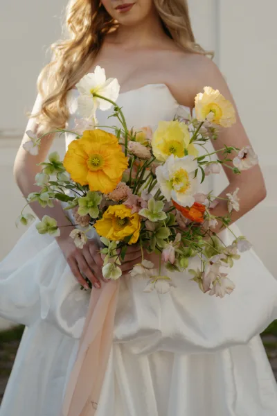 Bride in a strapless gown holding a large yellow and white bridal bouquet at a Villa Borghese wedding in Rome