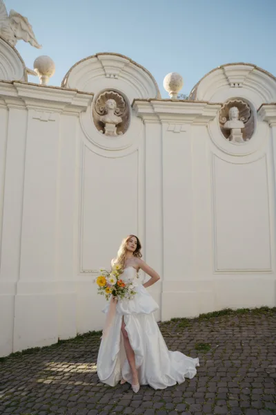 Bride in a white gown standing before the ornate classical facade of Villa Borghese during a Rome wedding