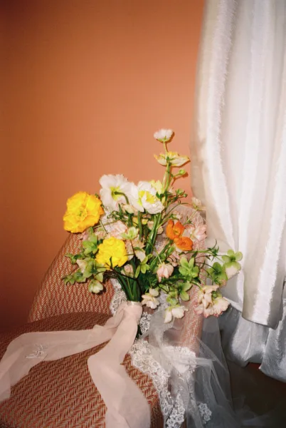 Yellow and orange wedding floral arrangement against a terracotta wall at Villa Borghese, Rome, styled by Zahra Studio Events