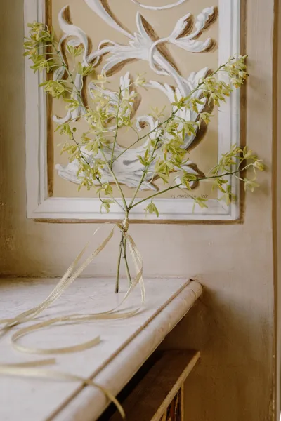 Yellow flowering branches in a glass vase beside framed art, wedding styling at Villa Miani in Rome by Zahra Studio Events