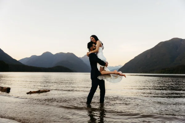 Groom tossing bride around in the water at Alouette Lake