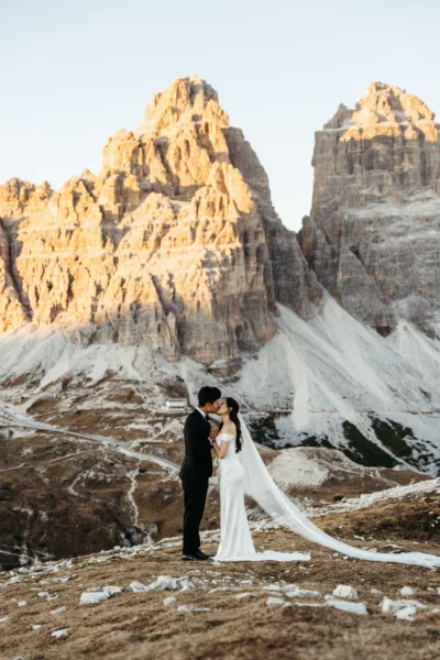 Bride and groom kissing in front of the setting sun on Tre Cime