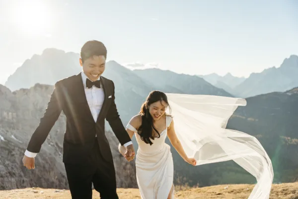 Bride and groom running up the mountain at sunset on Cadini di Misurina, with the veil blowing in the wind