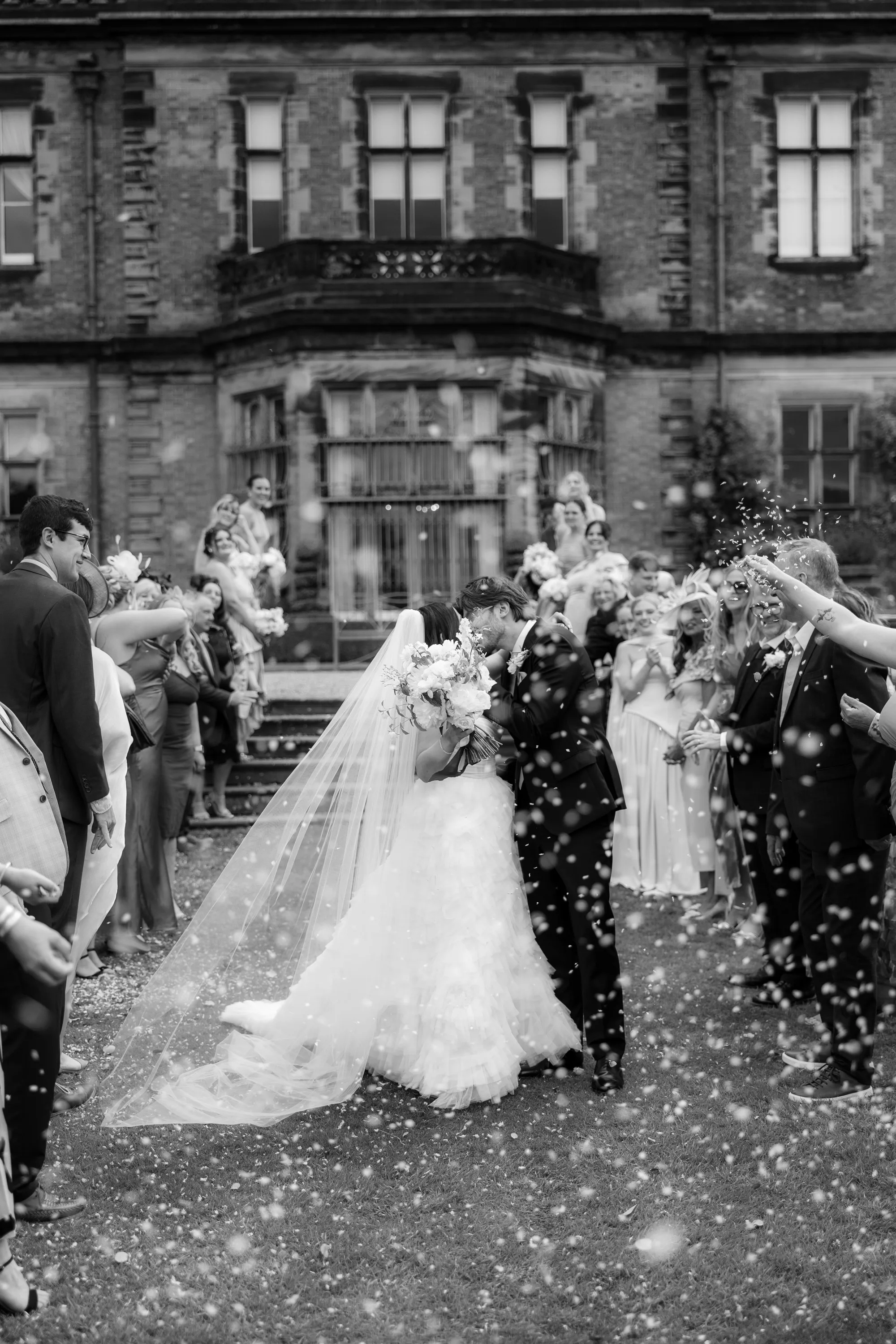 Capesthorne Hall Summer Wedding Jessica Sharpe Wedding Planner Jono Symonds Love My Dress.41 - Sophie & Dimitri's Beautiful, Relaxed & Elegant Wedding Weekend at Capesthorne Hall in Cheshire Bride and groom kissing in a shower of confetti outside Capesthorne Hall in Cheshire