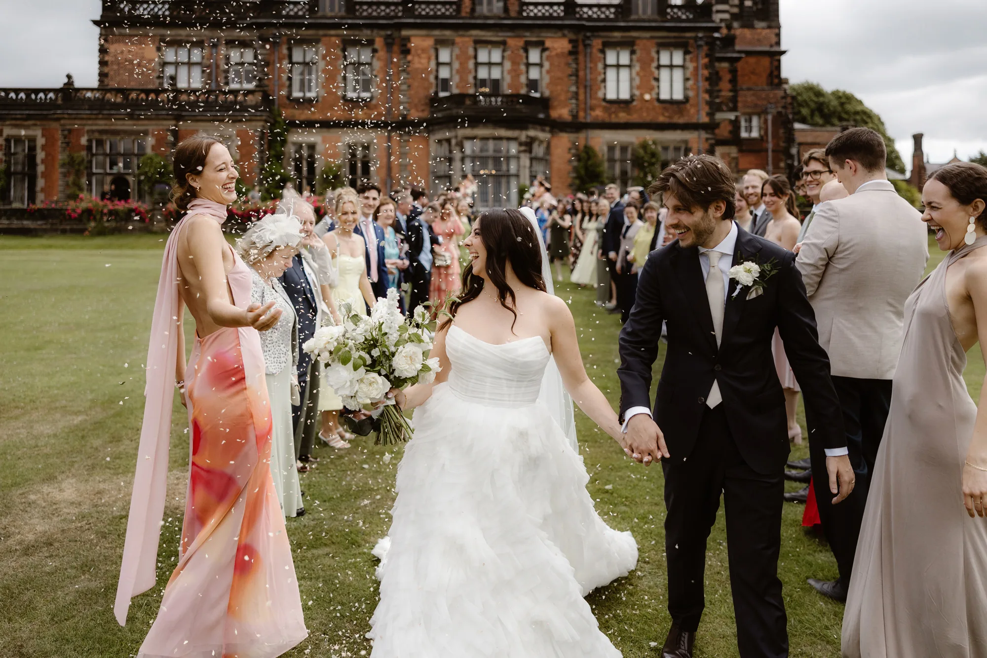 Capesthorne Hall Summer Wedding Jessica Sharpe Wedding Planner Jono Symonds Love My Dress.42 - Sophie & Dimitri's Beautiful, Relaxed & Elegant Wedding Weekend at Capesthorne Hall in Cheshire Bride smiling joyfully as she is showered in confetti in the garden at Capesthorne Hall in Cheshire.