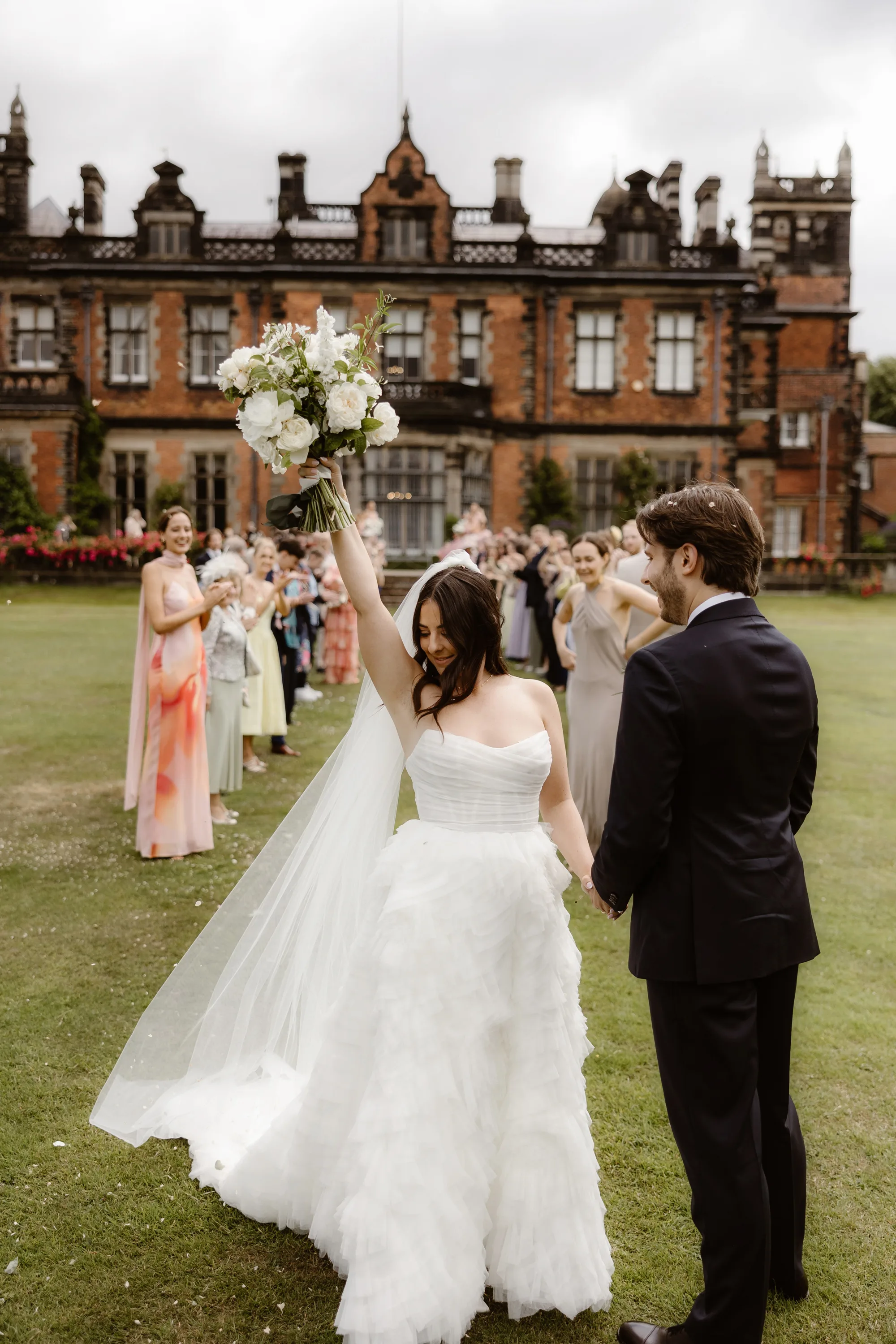 Capesthorne Hall Summer Wedding Jessica Sharpe Wedding Planner Jono Symonds Love My Dress.44 - Sophie & Dimitri's Beautiful, Relaxed & Elegant Wedding Weekend at Capesthorne Hall in Cheshire Bride wearing a Watters dress and raising her bouquet in the air after being showered in confetti at Capesthorne Hall in Cheshire.