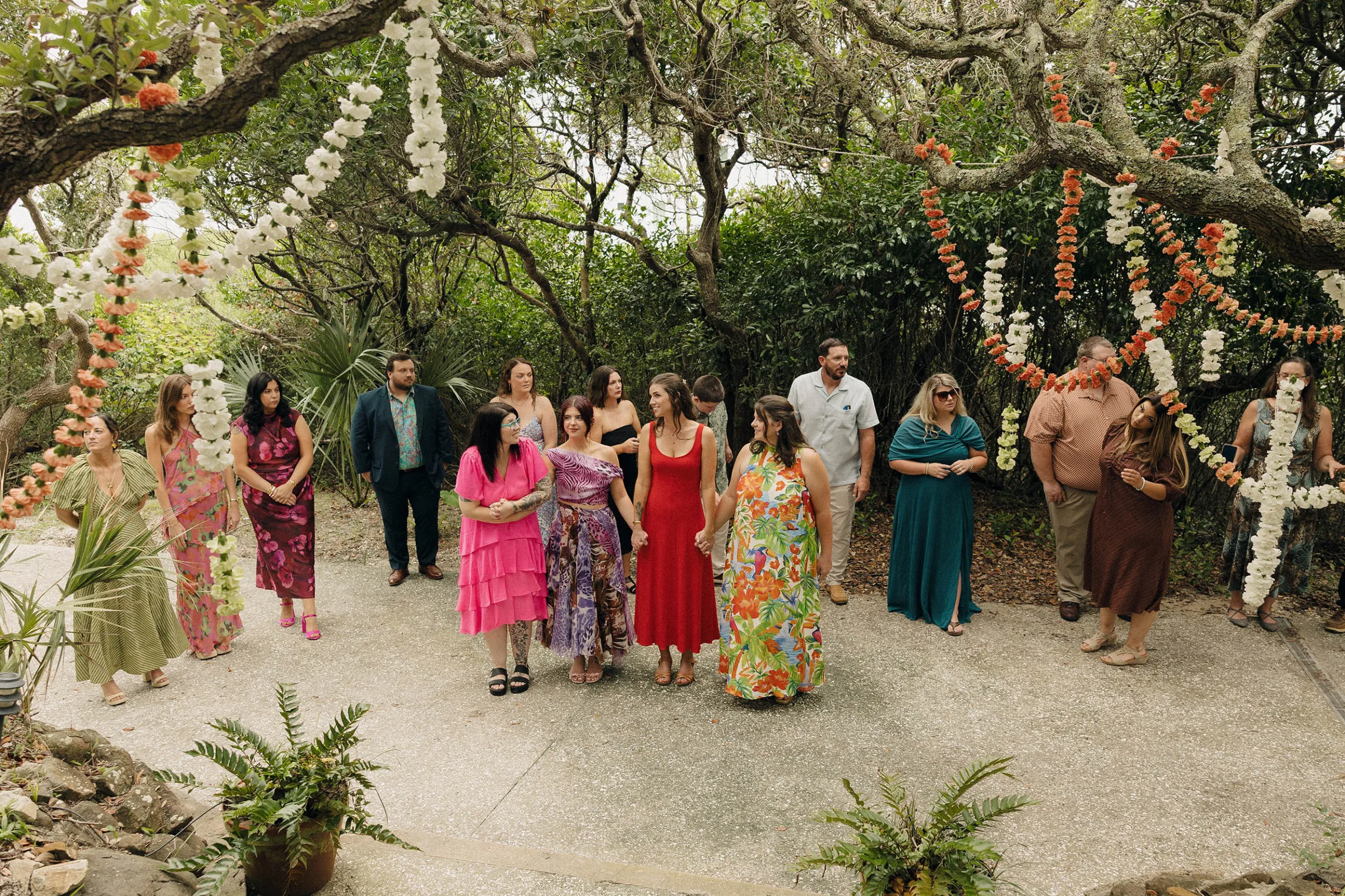 Danielle Frankel Bride Leslie DeAnne Photography.32 - Olivia in Danielle Frankel for her Intimate, Modern & Non-Traditional Wedding Guests gathered beneath the trees. at a private property wedding, garlands in orange, green and white hang above them from the trees.