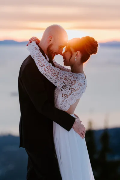 Bride and groom touching foreheads as the sun sets through them during their winter elopement on Grouse Mountain