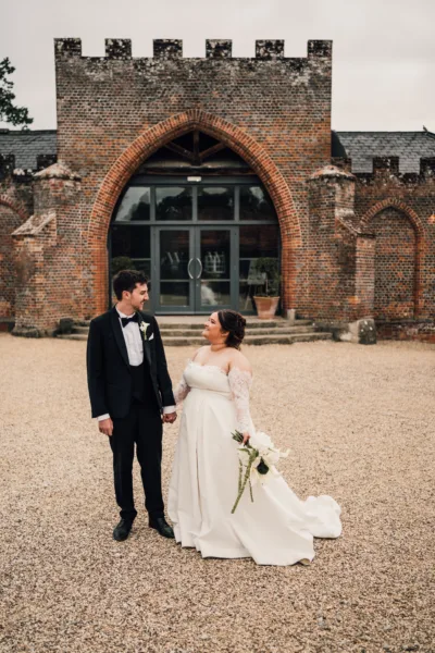 Bride and groom standing in the grounds of a brick arch wedding venue
