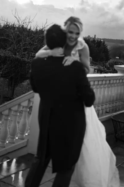 Black and white portrait of a groom holding a bride in an off-the-shoulder wedding dress