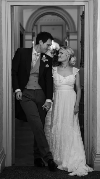 Black and white photo of a bride and groom walking through the entrance of Mansion House