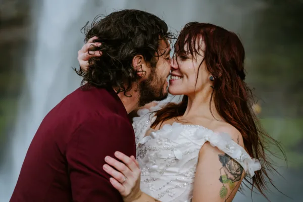 Bride and groom kissing in front of Icelandic waterfall