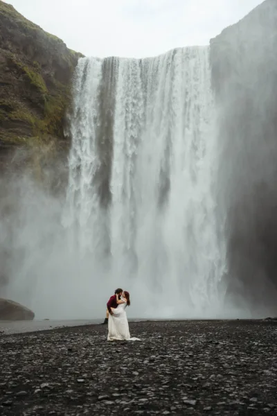 Groom dipping bride in from of waterfall in Iceland