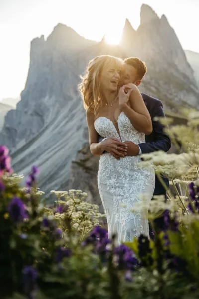 Bride and groom in a field of flowers on top of Seceda at sunrise
