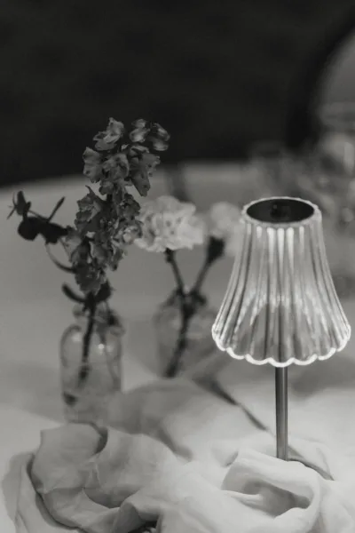 Black and white close-up of wedding florals and a decorative table lamp