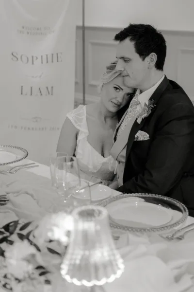 Black and white portrait of a bride in lace at a candlelit reception table