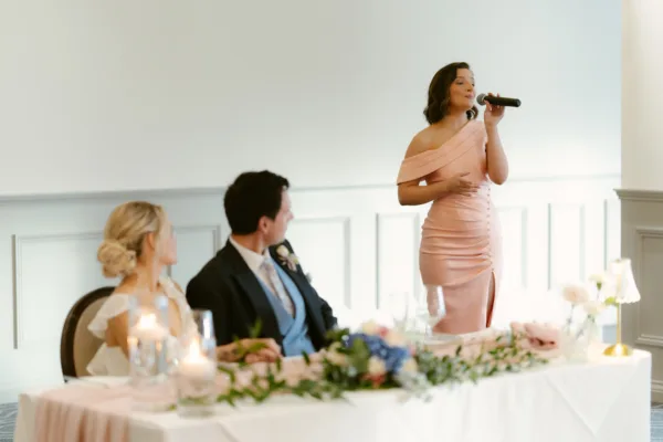 Singer in a pink dress performing beside a bride and groom at the wedding top table