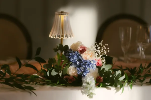 Close-up of a wedding floral centrepiece with blue hydrangeas, white blooms, and greenery