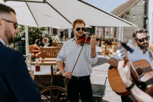 Musicans play outdoors during a sunny wedding drinks reception in Kent