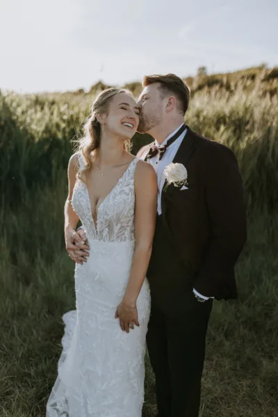 Bride and groom in front of tall grasses at The Harty Estate Kent wedding venue