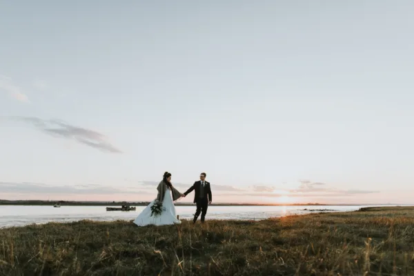 Bride and groom walk hand in hand during their winter wedding, beside the Kent coast