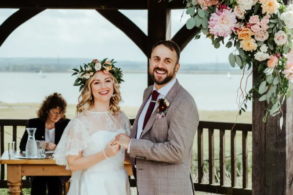 Newlyweds smiling in front of the Kent estuary at The Harty Estate