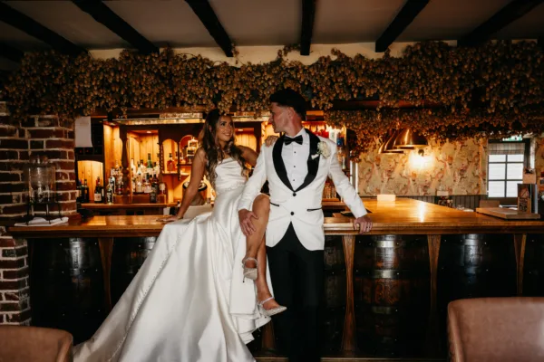 Newlyweds pose on the bar of The Harty Estate's private wedding pub
