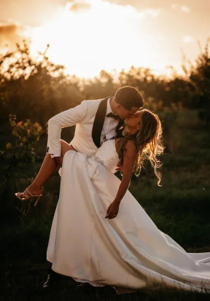 Newlyweds kiss at sunset in the Harty Estate orchard