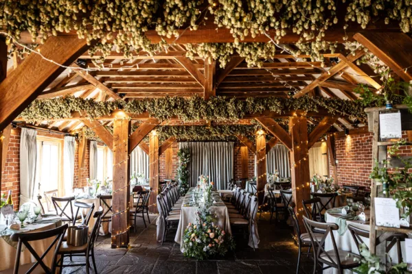 Rustic Kent wedding barn dressed for wedding breakfast with a central top table