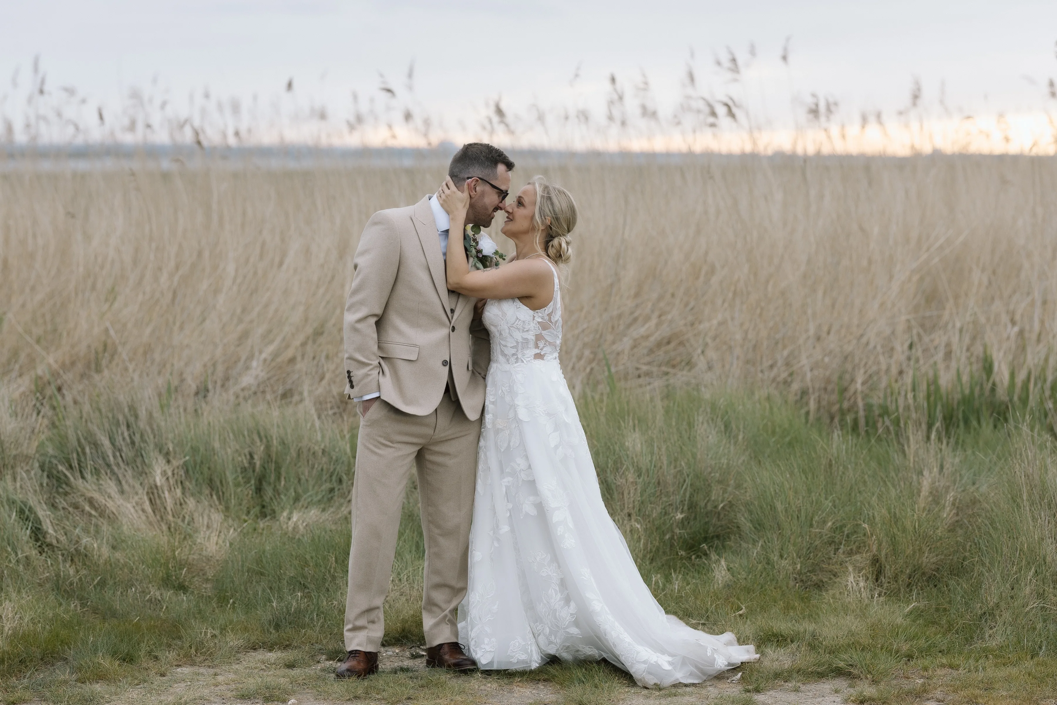 Bride and groom in front of tall water grasses at their coastal Kent wedding venue