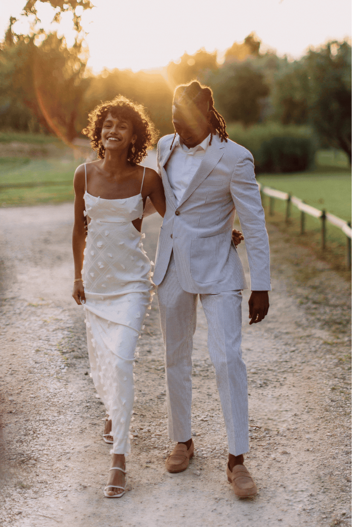 Playful Black model bride and groom. She wears Maison Thérèse Chopinet and he wears a pale linen suit as they run and pose for romantic images during golden hour.