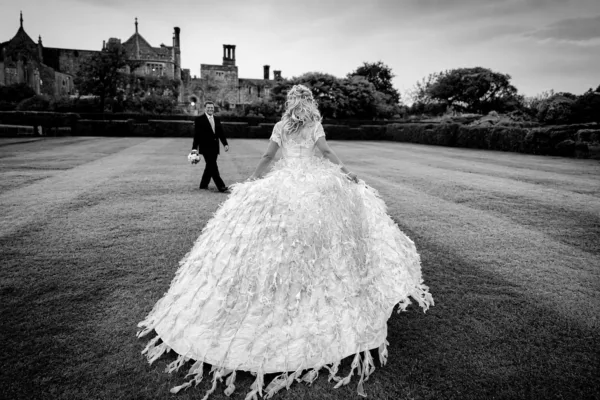 Bride in an elaborate textured wedding gown walking towards the groom